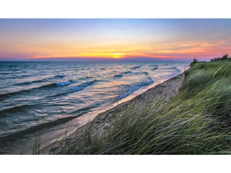 beautiful sunset at Lake Michigan and the lied grass demonstrating the pace of wind flowing at this beautiful coast of Lake Michigan but is it bossible to swim in such fast flowing Lake Michigan.
