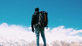 man standing near mountains with a backpack on his back