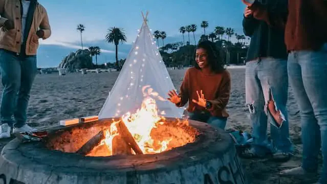 A group of people sitting around campfire to enjoy beach camping