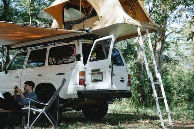 A man sitting under a roof top tent while car camping