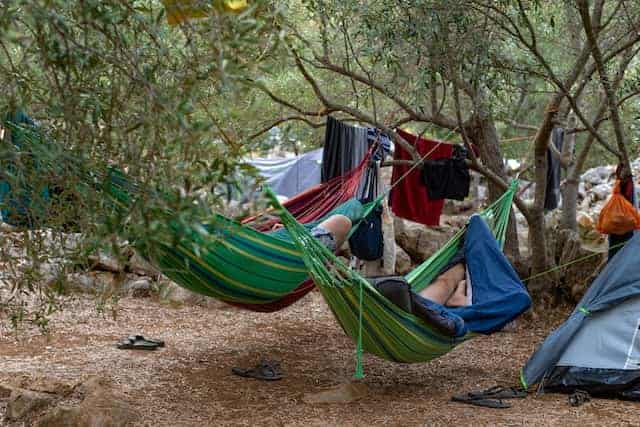 Two person sleeping in green hammocks in a hammock camping