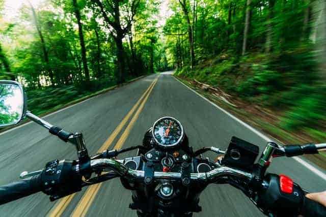 A person hands are showing in POV mode driving motorcycle. Motorcycle camping