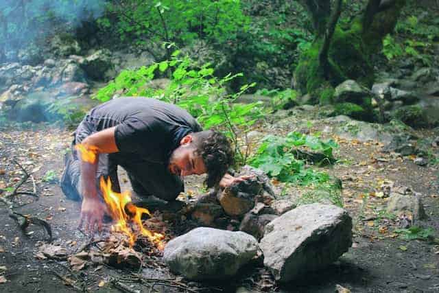 a man burning campfire to enrich the survival camping
