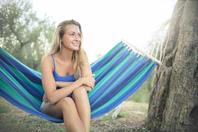 The girl sitting on a hammock thinking about how to set up top quilts for this blue lightweight hammock