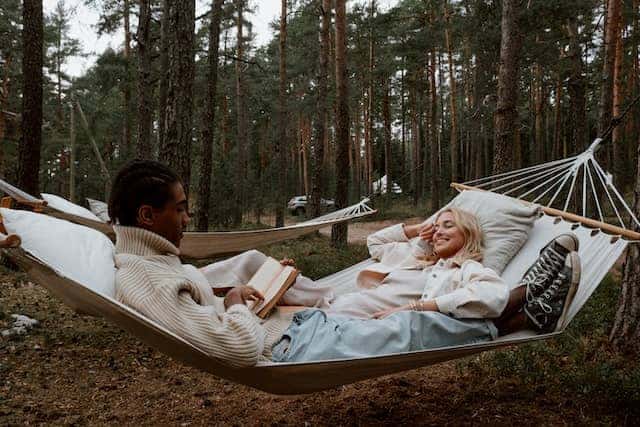 men and women lying in a white hammock reading about underquilts so that they can better prepare.