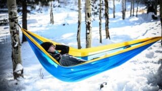 a person laying in a hammock in the snow