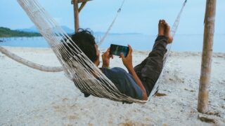 person on hammock using smartphone